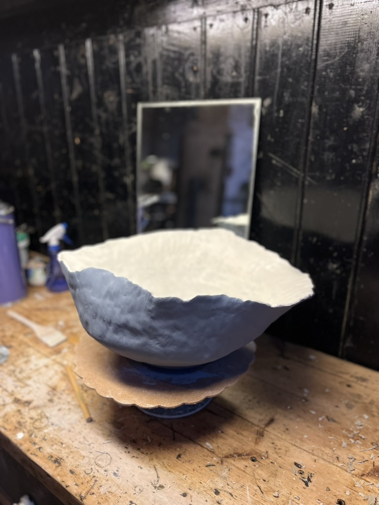 Hand-formed clay bowl on a workbench